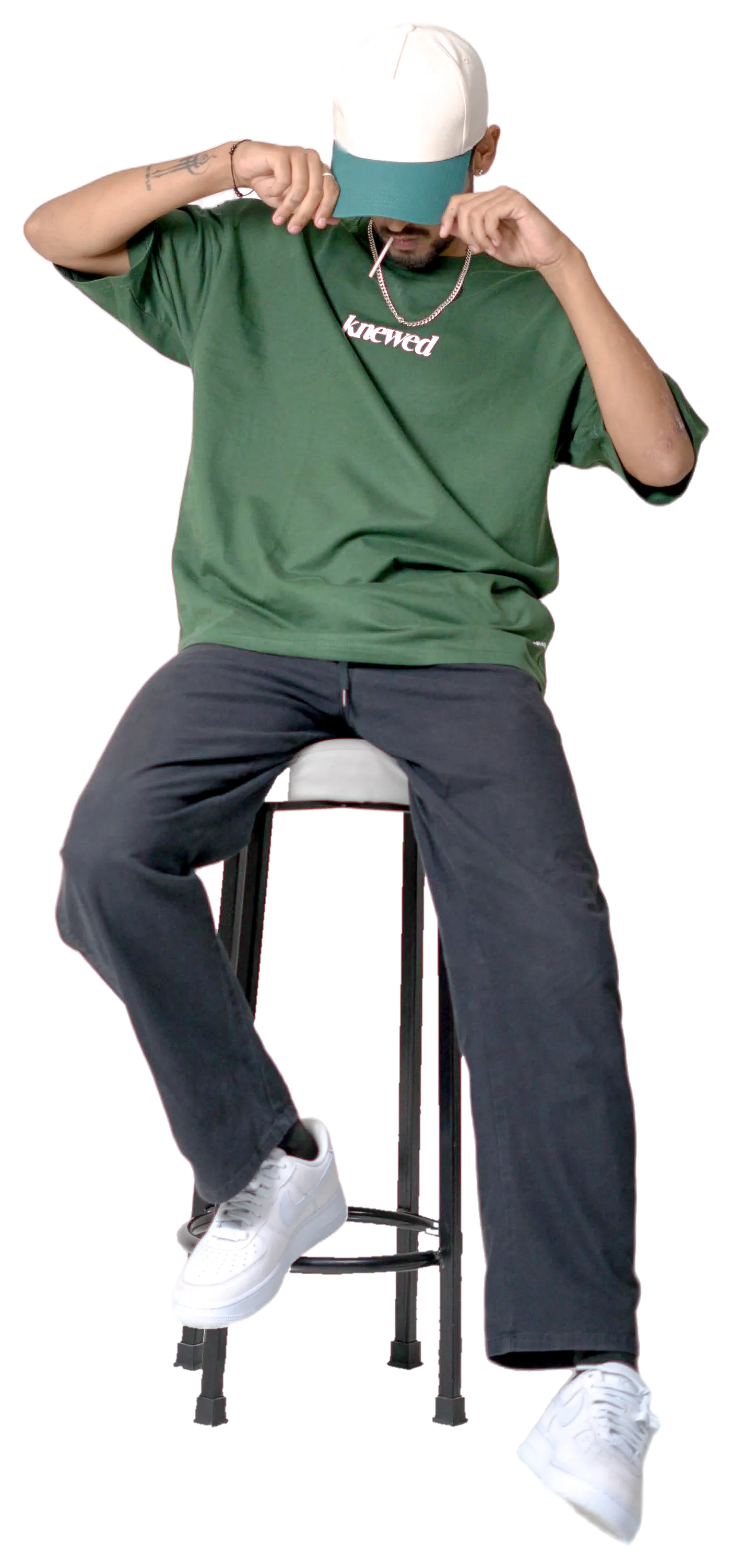 Model in a green Knewed oversized tee on a stool
